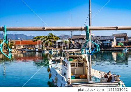 [Important Preservation District for Groups of Traditional Buildings] Dewajima Island: Early spring scenery of fishing boats and the Nishihato settlement, Mugi-cho, Kaifu-gun, Tokushima Prefecture 141335022
