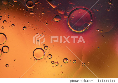 Oil drops creating an abstract pattern with gradients of orange, red, and yellow colors 141335144