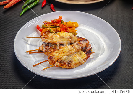 Grilled chicken skewers with melted cheese and sauteed bell peppers on white plate Grilled chicken skewers with melted cheese and sauteed bell peppers on white plate 141335676