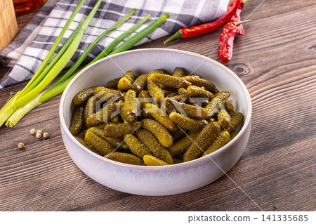 Rustic still life with pickled gherkins in grey bowl, green onions, red chili peppers, peppercorns on wooden table Rustic still life with pickled gherkins in grey bowl, green onions, red chili peppers, peppercorns on wooden table 141335685