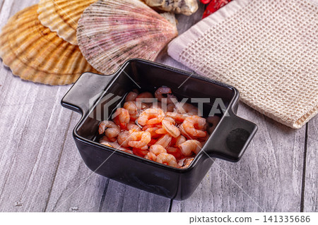 Cooked peeled shrimp in black ceramic bowl on rustic gray wood with seashells Cooked peeled shrimp in black ceramic bowl on rustic gray wood with seashells 141335686
