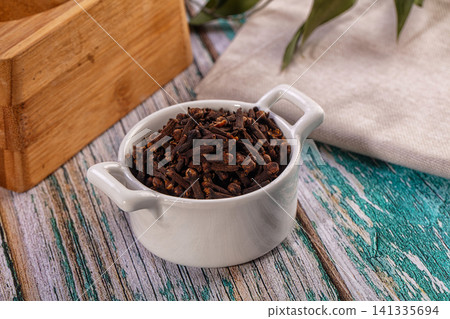 Aromatic dried cloves in a white ceramic bowl on a rustic painted wooden table Aromatic dried cloves in a white ceramic bowl on a rustic painted wooden table 141335694
