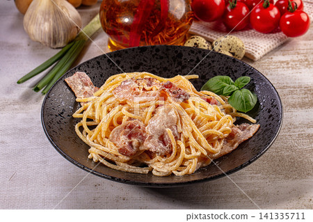 Spaghetti carbonara plate with crispy bacon and fresh basil Spaghetti carbonara plate with crispy bacon and fresh basil 141335711