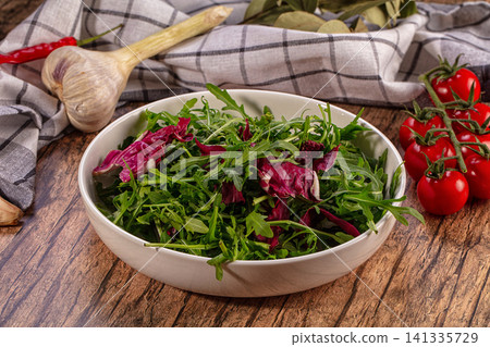Fresh arugula radicchio salad bowl with cherry tomatoes garlic on rustic wood Fresh arugula radicchio salad bowl with cherry tomatoes garlic on rustic wood 141335729