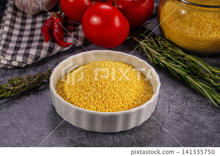 Raw couscous in white bowl with tomatoes garlic rosemary and chili peppers Raw couscous in white bowl with tomatoes garlic rosemary and chili peppers 141335750