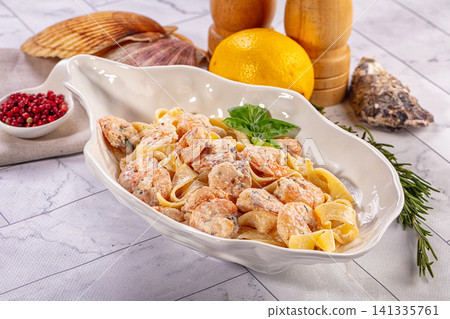 Shrimp fettuccine in creamy sauce with basil on marble table with lemon and shells Shrimp fettuccine in creamy sauce with basil on marble table with lemon and shells 141335761