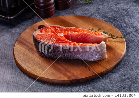 Raw salmon fillet on wooden cutting board with herb garnish Raw salmon fillet on wooden cutting board with herb garnish 141335804