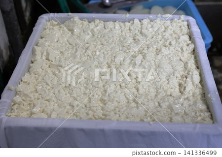 The freshly made tofu dough being packed into a mold. The freshly made tofu dough being packed into a mold. 141336499
