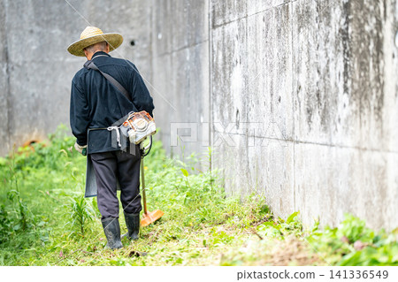 Elderly man mowing with a mower in early summer Elderly man mowing with a mower in early summer 141336549