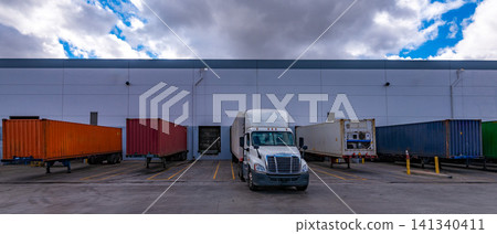 A trailer truck and containers parked at a loading dock in a logistics warehouse. A trailer truck and containers parked at a loading dock in a logistics warehouse. 141340411