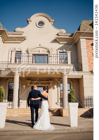 Happy and in love bride and groom at the entrance to a beautiful building Happy and in love bride and groom at the entrance to a beautiful building 141341436