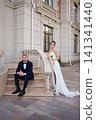 A bride and groom in love and happy on the steps at the entrance to a building. 141341440