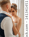 Portrait of a beautiful groom and a bride by the window 141341451