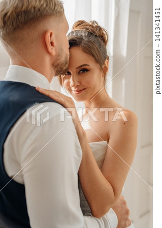 Portrait of a beautiful groom and a bride by the window Portrait of a beautiful groom and a bride by the window 141341451