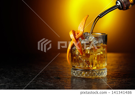 Old-fashioned cocktail in a fogged up glass on a black stone table. Old-fashioned cocktail in a fogged up glass on a black stone table. 141341486