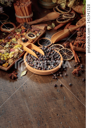 Rustic arrangement of juniper berries, dried citrus, cinnamon and aromatic herbs on a wooden table. Rustic arrangement of juniper berries, dried citrus, cinnamon and aromatic herbs on a wooden table. 141341528