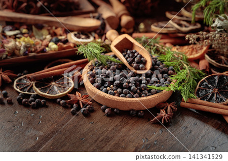 Juniper berries, dried orange slices, cinnamon sticks and wild herbs arranged in a rustic setting. Juniper berries, dried orange slices, cinnamon sticks and wild herbs arranged in a rustic setting. 141341529