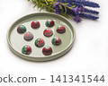 Collectible handmade tempered chocolate sweets with a glossy painted body on a round plate 141341544