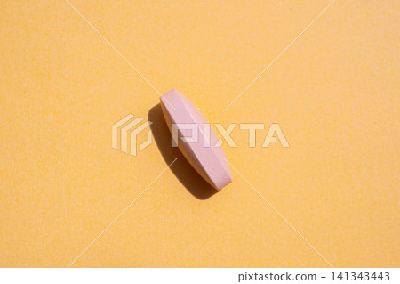 Pink medicine pill tablet on orange background 141343443