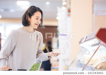 一位注重健康的女士在超市挑選豆腐。 一位注重健康的女士在超市挑選豆腐。 141343841