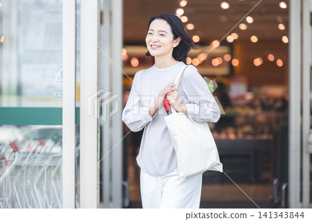 購物完畢後,一位女士面帶微笑地離開了超市。 購物完畢後,一位女士面帶微笑地離開了超市。 141343844
