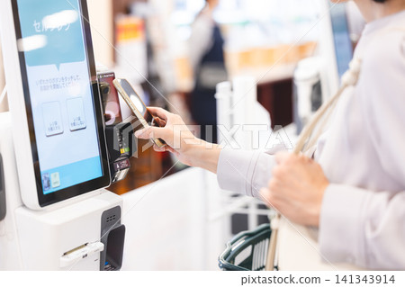 A hand using a smartphone to make a cashless payment at the supermarket checkout. A hand using a smartphone to make a cashless payment at the supermarket checkout. 141343914