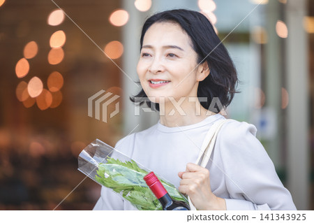 A middle-aged woman walking home from shopping with a smile on her face. A middle-aged woman walking home from shopping with a smile on her face. 141343925