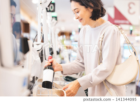 A housewife shopping and packing her groceries into her reusable bag. A housewife shopping and packing her groceries into her reusable bag. 141344095
