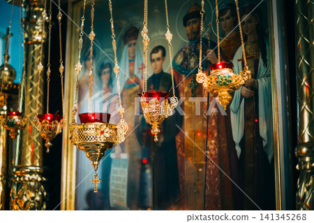 Golden Orthodox icon lamps hanging before an icon of Tsar Nicholas II's family. Golden Orthodox icon lamps hanging before an icon of Tsar Nicholas II's family. 141345268