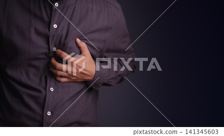 Adult man holding his chest experiencing a severe heart attack and chest pain. Medical, healthcare, and cardiovascular disease emergency concept. 141345603