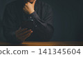 Serious business man thinking while holding a mobile phone in a dark room. Modern smartphone technology concept. 141345604