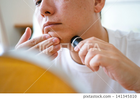 一位四十多歲的男子用電動刮鬍刀刮鬍子的特寫。 141345810