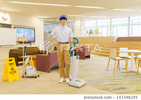 一位年輕的日本男清潔工正在用吸塵器打掃辦公大樓。照片由東京電子電波學園提供。 一位年輕的日本男清潔工正在用吸塵器打掃辦公大樓。照片由東京電子電波學園提供。 141346285