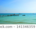 Tropical landscape with turquoise ocean water, wooden pier, and fishing boats 141346359