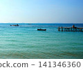 Tropical landscape with turquoise ocean water, wooden pier, and fishing boats 141346360