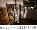 A traditional Japanese-style shoji screen, with its vibrant paper-cut patterns illuminated by light, is placed in a traditional Japanese room. January 2024. 141346449