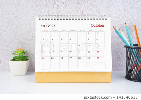 October 2027 Desk Calendar with wooden pencil on white table. October 2027 Desk Calendar with wooden pencil on white table. 141346613