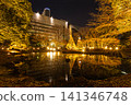 A panoramic view of Koishikawa Korakuen Garden at night, with countless rays of light and snow-covered trees reflected in the large pond. January 2024. 141346748