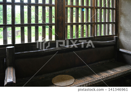 一扇迷人的格子窗和一扇格子門;一張厚實的木長凳;以及歷史悠久的老房子裡寧靜的室內景象。 一扇迷人的格子窗和一扇格子門;一張厚實的木長凳;以及歷史悠久的老房子裡寧靜的室內景象。 141346961
