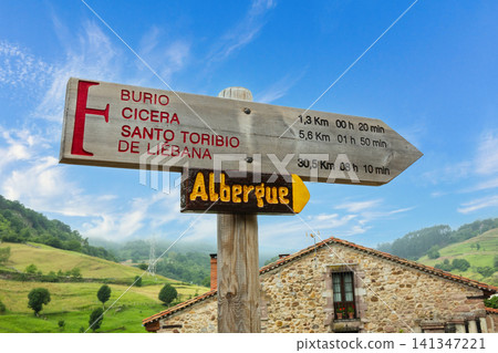 Camino de Santiago wooden direction sign with albergue arrow in green valley Camino de Santiago wooden direction sign with albergue arrow in green valley 141347221