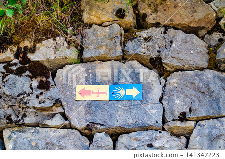 Camino de Santiago symbols and directional arrows on a stone wall Camino de Santiago symbols and directional arrows on a stone wall 141347223