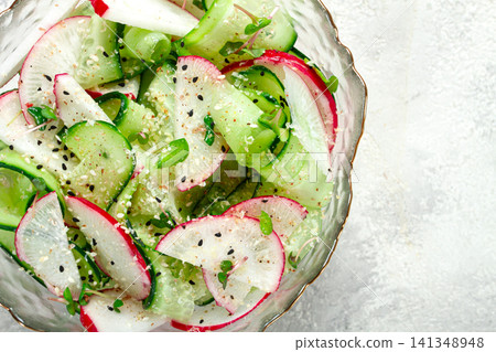 Fresh cucumber and radish salad served in a clear bowl on a light surface Fresh cucumber and radish salad served in a clear bowl on a light surface 141348948