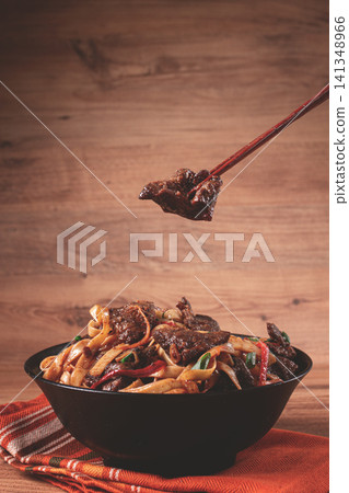 Udon noodles with beef in Mongolian style, with green onions and vegetables, homemade, on a wooden table, Udon noodles with beef in Mongolian style, with green onions and vegetables, homemade, on a wooden table, 141348966