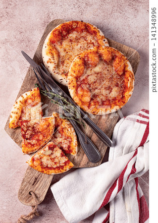 Four pizzetta Margaritas, on a cutting board, on a light gray surface, top view, 141348996