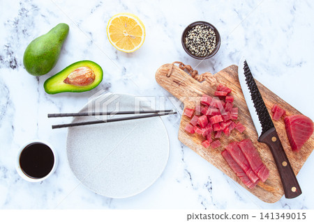 Cooking fresh tuna with ingredients on a marble countertop, ingredients for making sushi and tuna tartare Cooking fresh tuna with ingredients on a marble countertop, ingredients for making sushi and tuna tartare 141349015