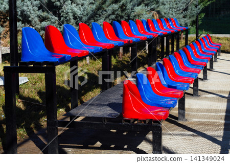 Bright colored seating arrangements lined up in a sports area on a sunny day Bright colored seating arrangements lined up in a sports area on a sunny day 141349024