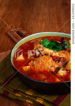 Souzi soup. Georgian dish, meat with oats, tomato sauce and herbs, on a wooden table Souzi soup. Georgian dish, meat with oats, tomato sauce and herbs, on a wooden table 141349032