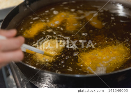 炸豬排(tonkatsu)在油中炸製的場景;餐廳裡的油炸過程;酥脆外皮的圖片。 炸豬排(tonkatsu)在油中炸製的場景;餐廳裡的油炸過程;酥脆外皮的圖片。 141349093