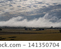 A waterfall of clouds cascading down a hill and autumn farmland. 141350704