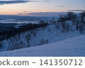A view of the plains at dusk from a snow-covered ridge. 141350712